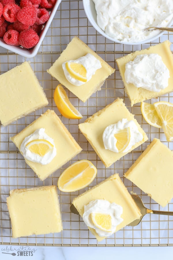 Lemon bars on a baking rack with lemon wedges.