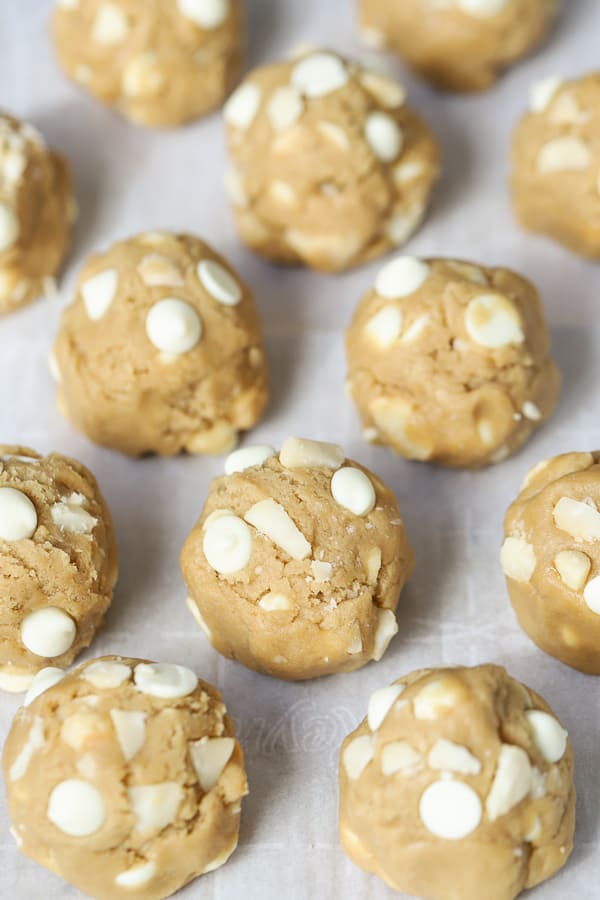 Cookie dough balls with white chocolate chips on a baking sheet