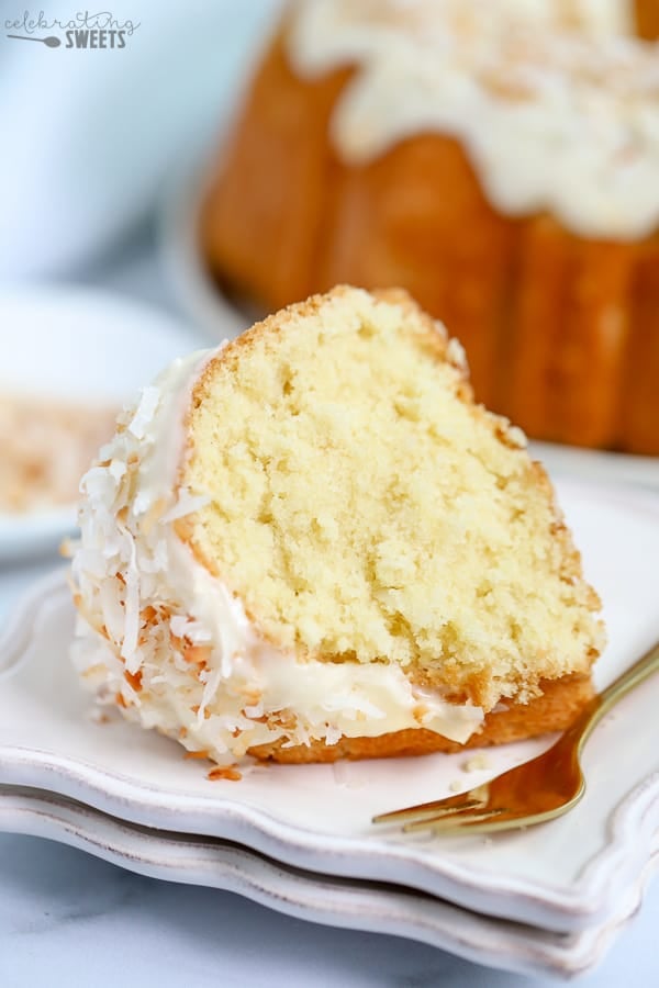 Slice of coconut bundt cake on a white plate. with a gold fork.