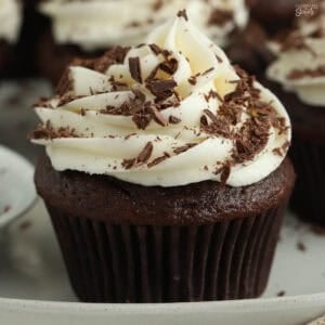 Closeup of a chocolate cupcake topped with cream cheese frosting and chocolate shavings.
