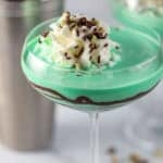 Grasshopper drink in a coupe glass topped with whipped cream and chocolate sprinkles.