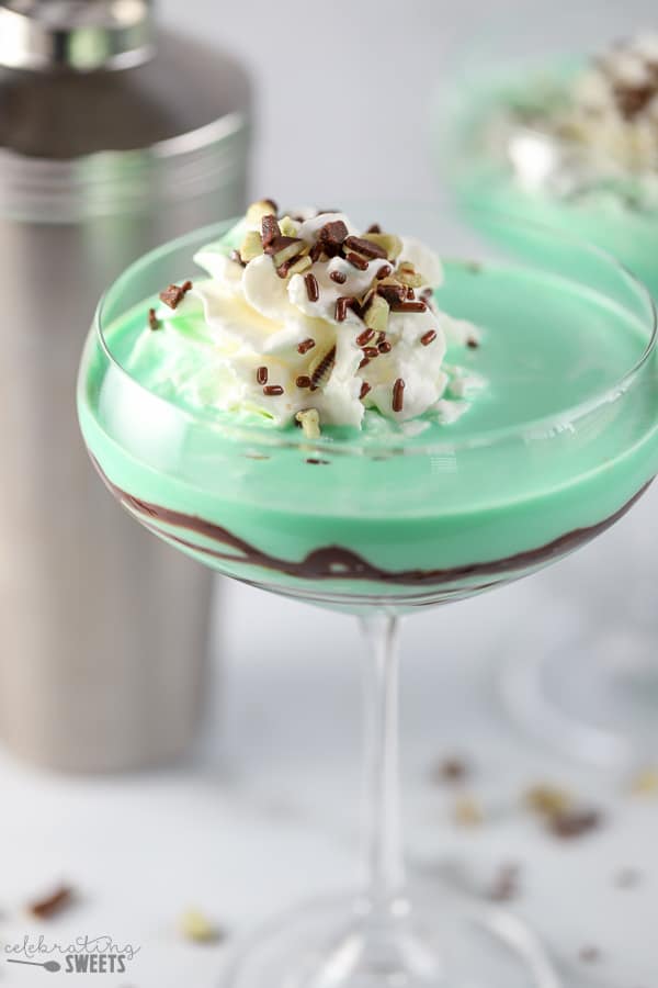 Green grasshopper drink in a stemmed glass with swirled with chocolate syrup.