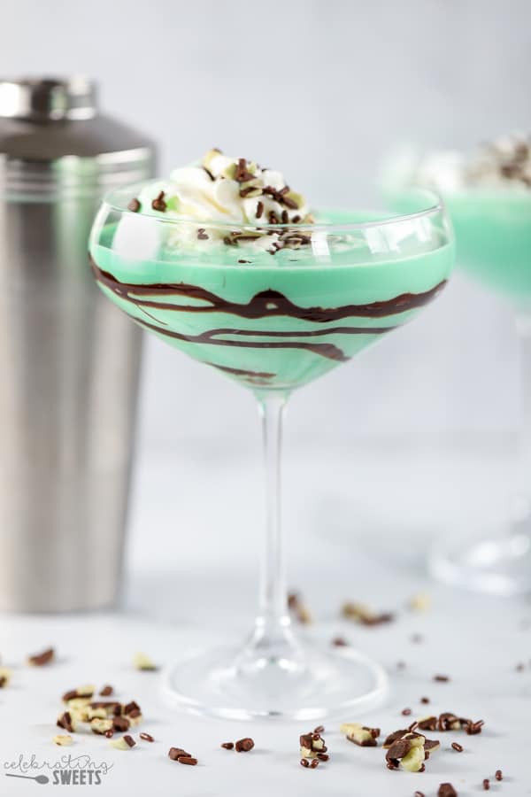 Green grasshopper drink in a stemmed glass with swirled with chocolate syrup.