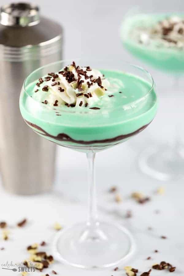 Green grasshopper drink in a stemmed glass with swirled with chocolate syrup.