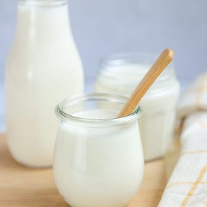 Three glass jars filled with buttermilk sitting on a wood board.