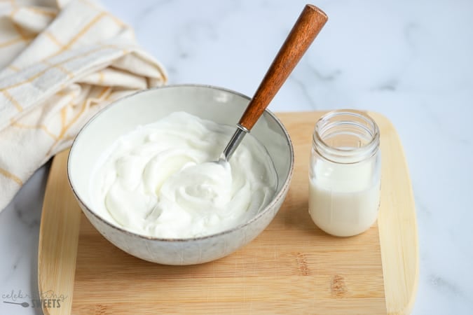 Bowl of yogurt and jar of milk on a wood board (how to make buttermilk)
