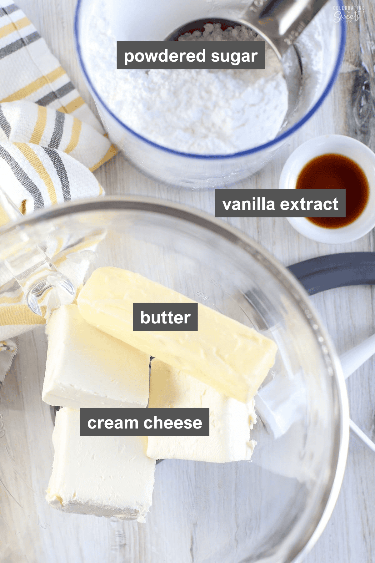Cream cheese and butter in a glass bowl, vanilla extract, and a plastic container of powdered sugar.
