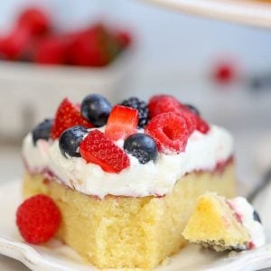 A slice of cake topped with whipped cream and mixed berries.