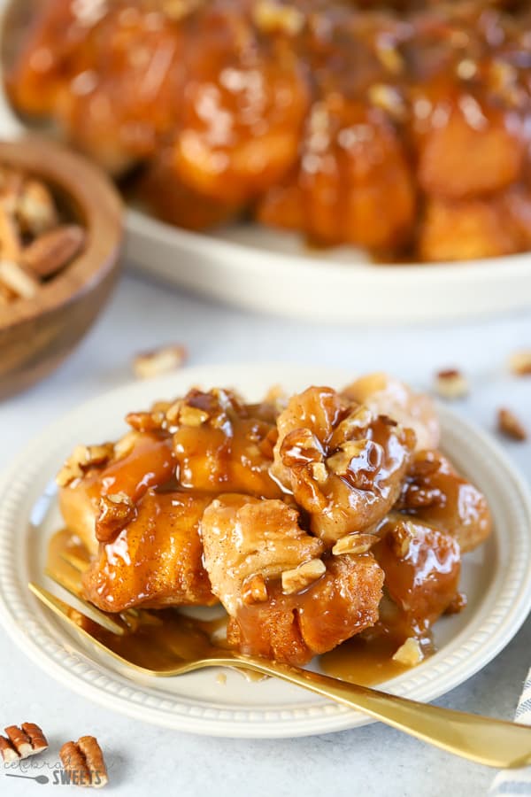 Caramel pecan monkey bread on a white plate with a gold fork.