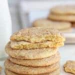 Stack of snickerdoodle cookies with a glass jar of milk in the background.