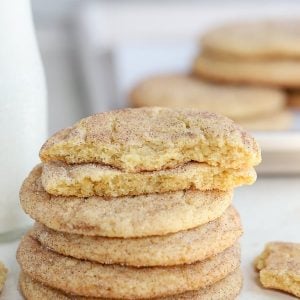 Stack of snickerdoodle cookies with a glass jar of milk in the background.