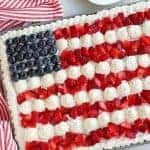 American flag cake decorated with strawberries, blueberries and white frosting.