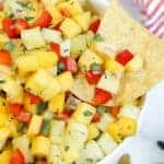 Bowl of pineapple mango salsa with a tortilla chip.