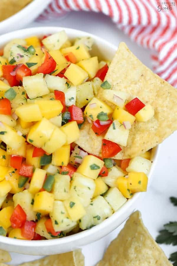 Bowl of pineapple mango salsa with a tortilla chip.