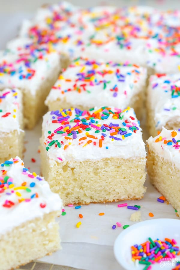 Slice of vanilla cake with vanilla frosting and sprinkles.