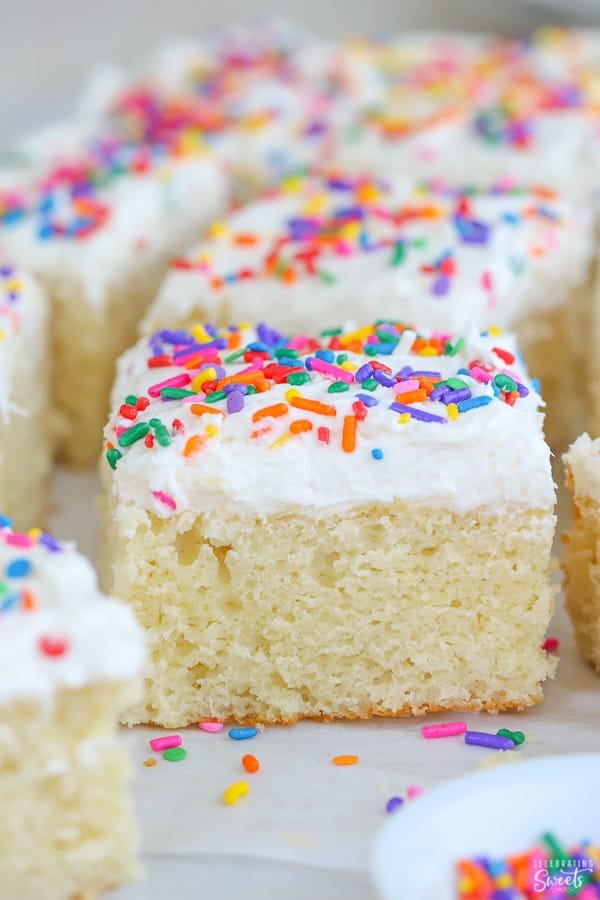 Slice of vanilla cake with vanilla frosting and sprinkles.