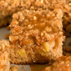 Apple crumb cake topped with brown sugar sauce in a metal baking pan.