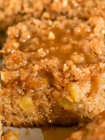 Apple crumb cake topped with brown sugar sauce in a metal baking pan.