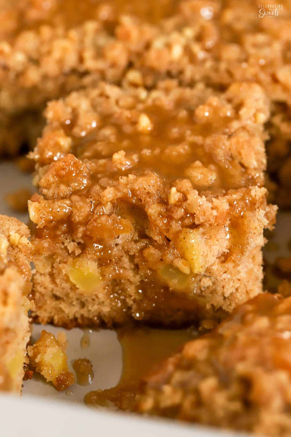 Apple crumb cake topped with brown sugar sauce in a metal baking pan.