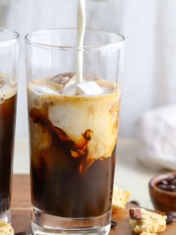 Milk being poured into iced coffee