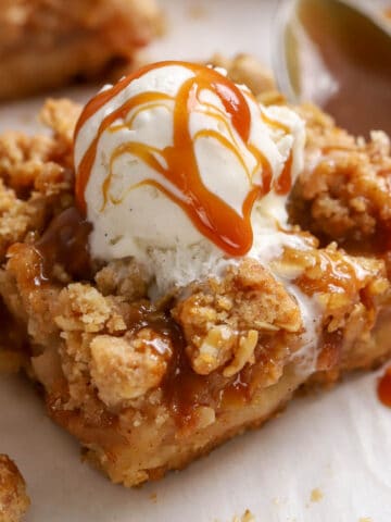 Apple crumb bar topped with vanilla ice cream and caramel sauce.