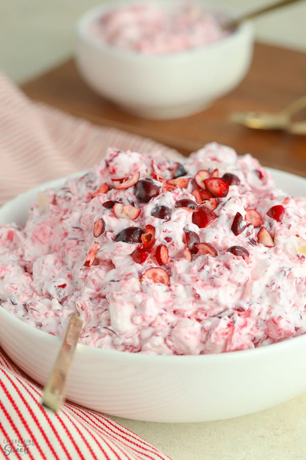 Creamy cranberry salad in a white bowl with a gold spoon.
