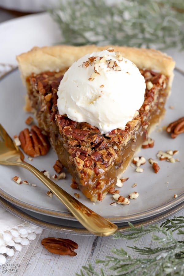 Slice of Pecan Pie topped with vanilla ice cream and chopped pecans. 