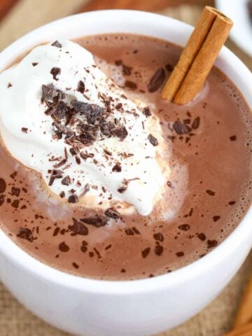 Mexican Hot Chocolate in a white mug topped with whipped cream and chocolate.