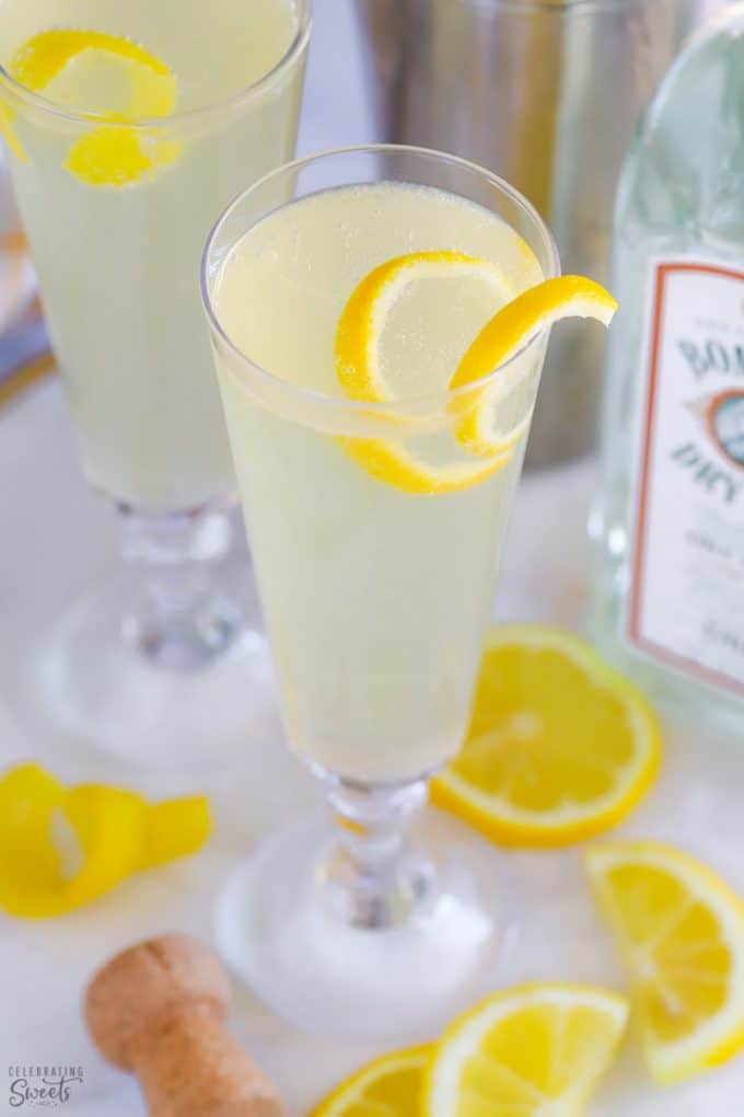 Light yellow French 75 cocktail in a champagne glass topped with a lemon twist.