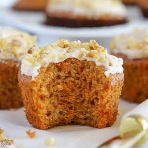 Carrot muffin topped with frosting and walnuts.