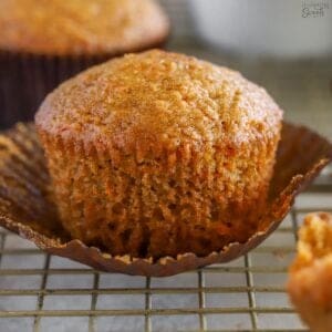 Carrot muffin in a brown wrapper on a wire rack