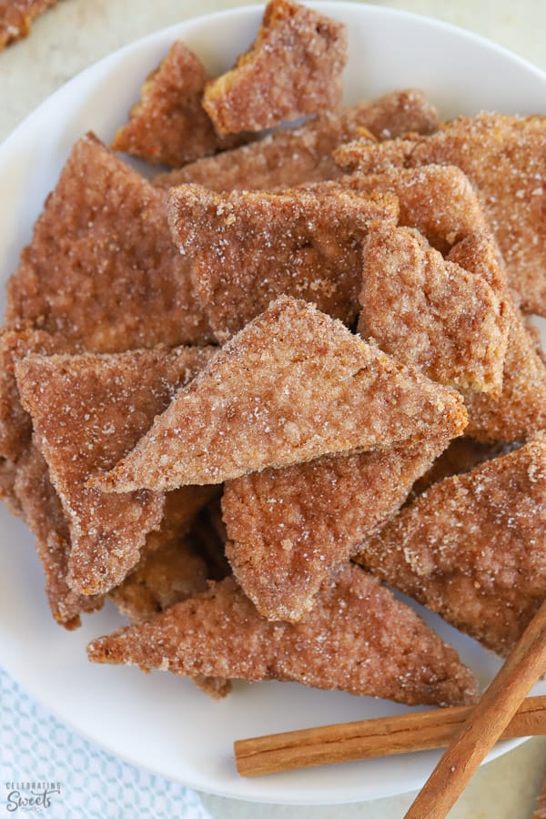 Triangle shaped cinnamon cookies piled on a white plate.