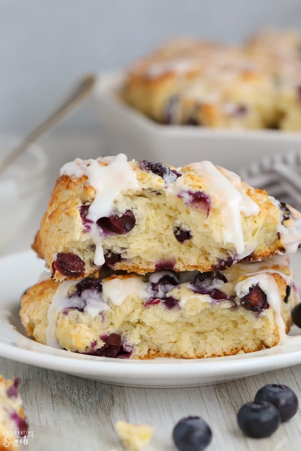 Blueberry scone broken in half stacked on top of each other on a white plate. 