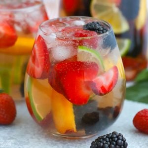 Glass of sangria filled with berries and lime.