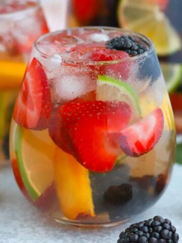 Glass of sangria filled with berries and lime.