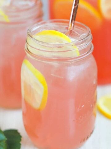 Mason jar filled with pink lemonade and lemon slices.