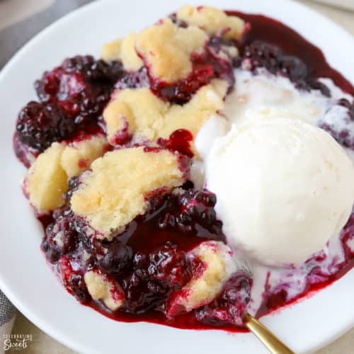 Blackberry Cobbler on a white plate with a scoop of vanilla ice cream.
