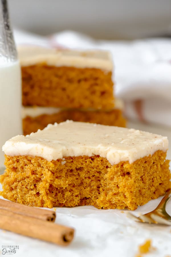 Sliced pumpkin bars topped with frosting on a piece of parchment paper.