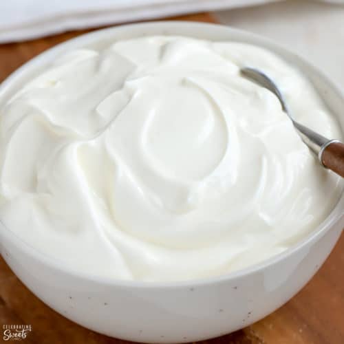 Sour cream in a white bowl with a wooden spoon.