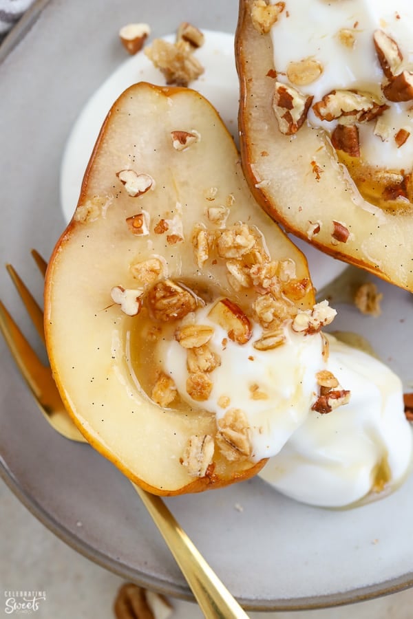 Baked pears on a plate with yogurt and granola. 