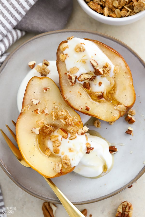 Baked pears on a plate with yogurt and granola.
