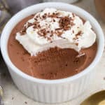 Chocolate mousse topped with whipped cream in a white ramekin