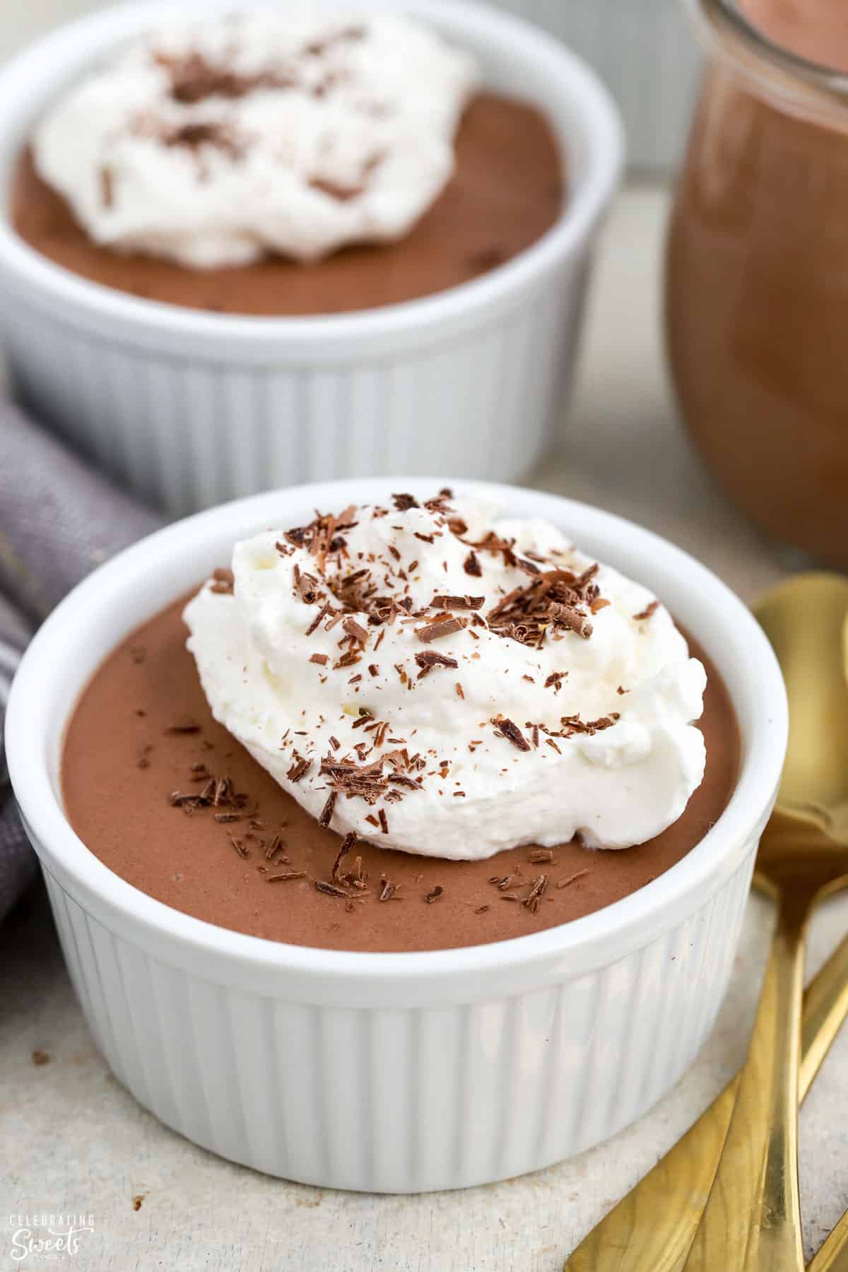 Chocolate mousse topped with whipped cream in a white ramekin