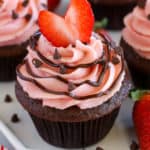 Chocolate cupcake topped with strawberry frosting and a heart shaped strawberry.