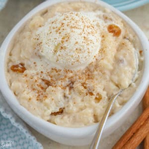 Rice pudding in a white bowl topped with ice cream and cinnamon.