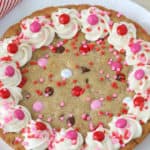 Cookie cake decorated with frosting and red and pink M&M's
