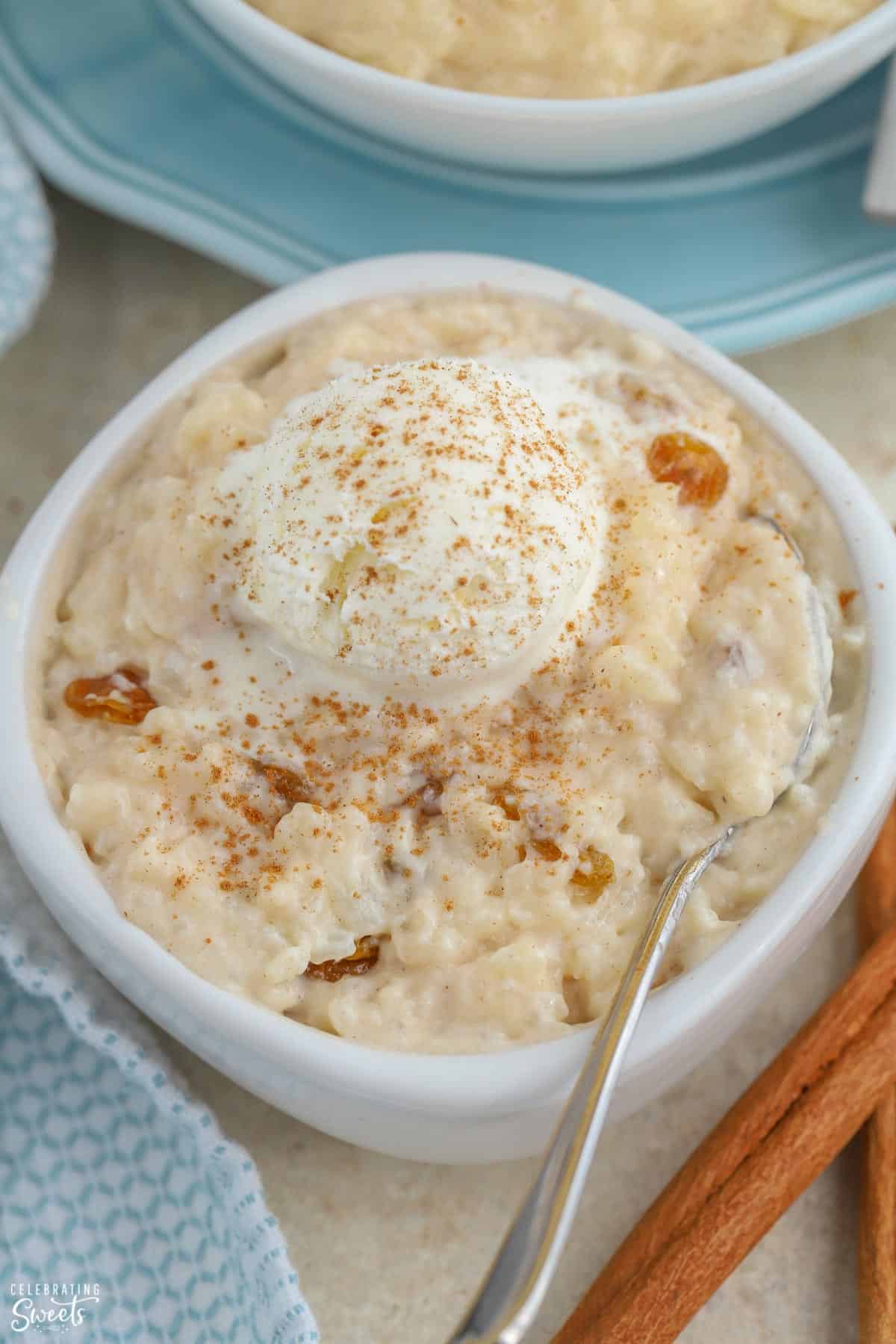 Rice pudding in a white bowl topped with ice cream and cinnamon.