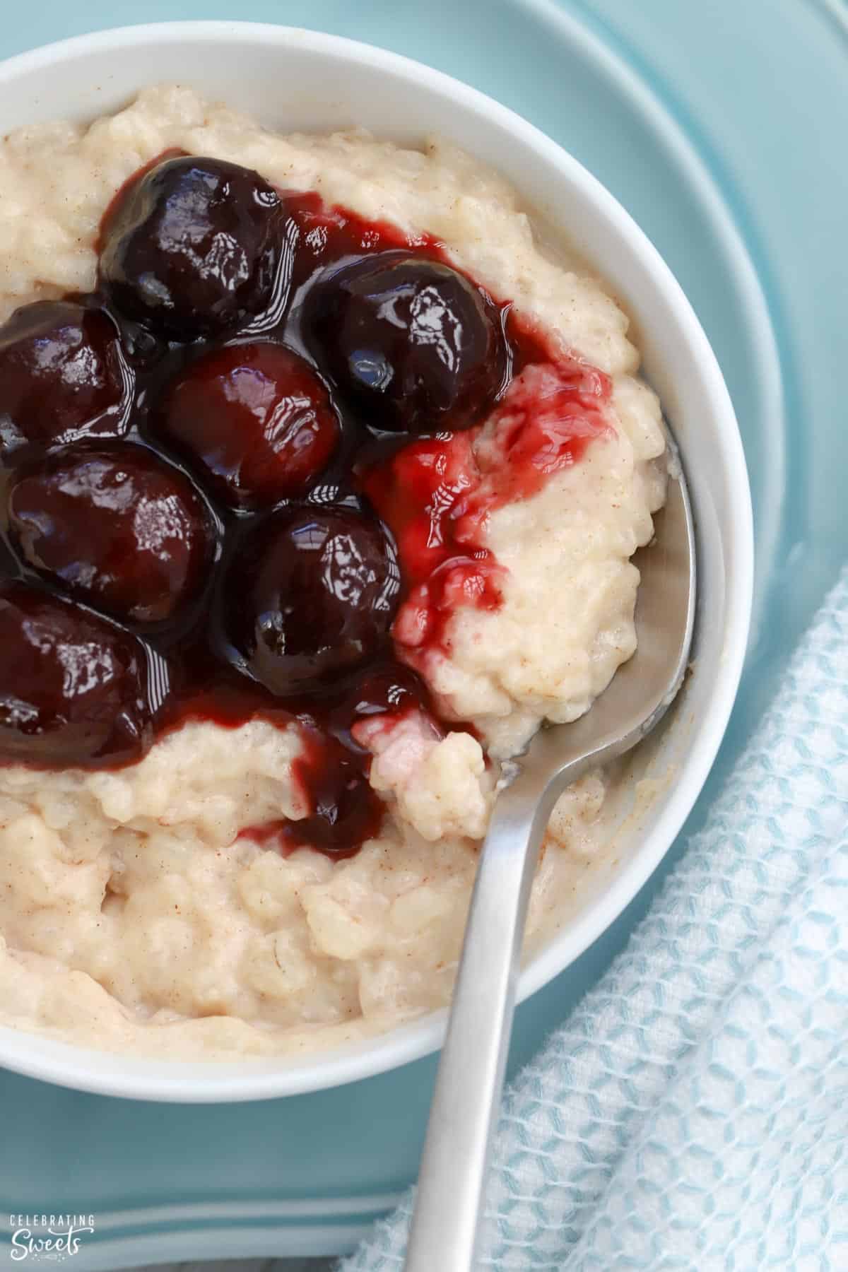 Rice pudding in a white bowl topped with cherries. 
