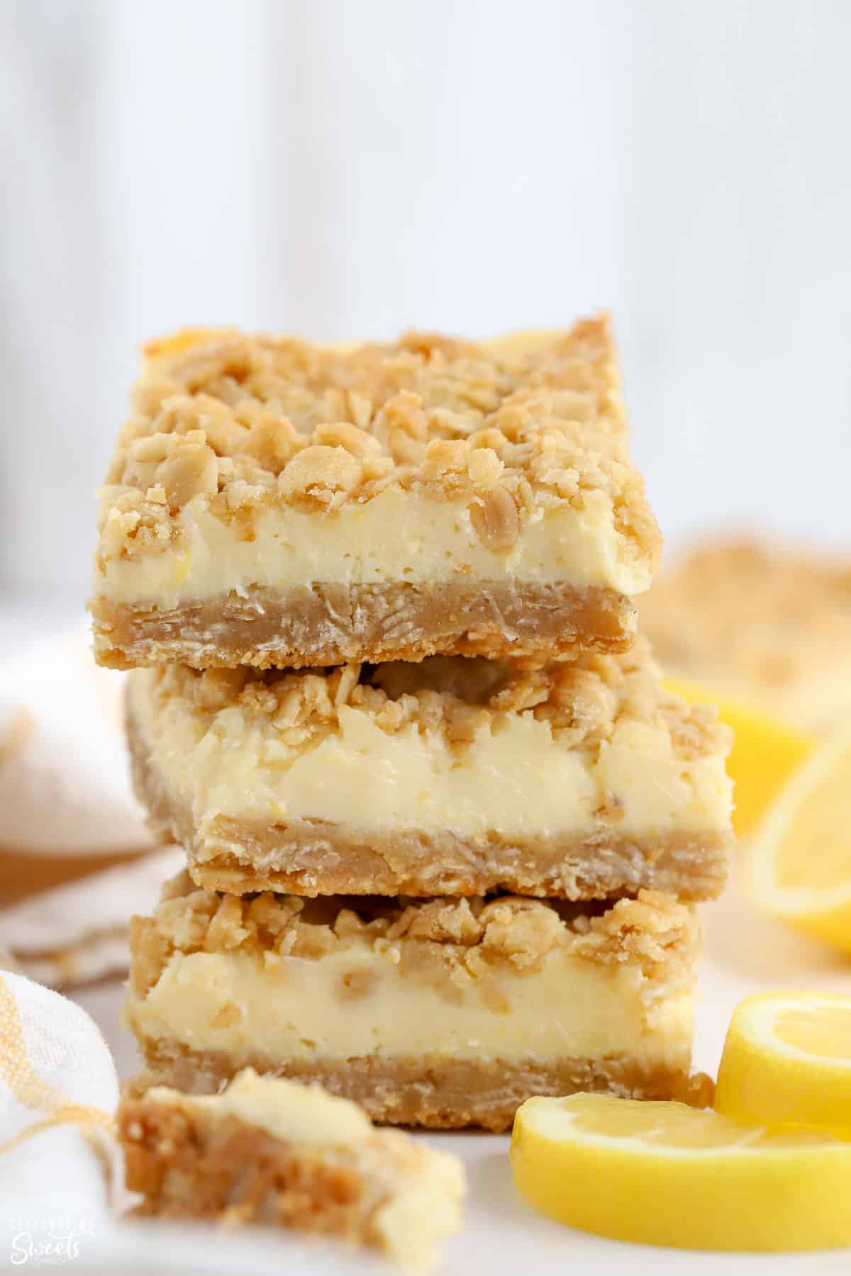 Stack of three lemon crumb bars with lemons in the background