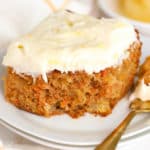 Slice of Pineapple Carrot Cake on a white plate with a gold fork